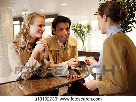 Couple checking in at hotel reception View Large Photo Image Stock Image - Couple checking in at hotel reception. Fotosearch