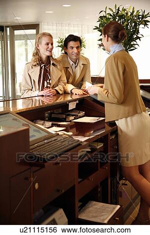 Stock Photograph - Couple checking in at hotel reception. Fotosearch
