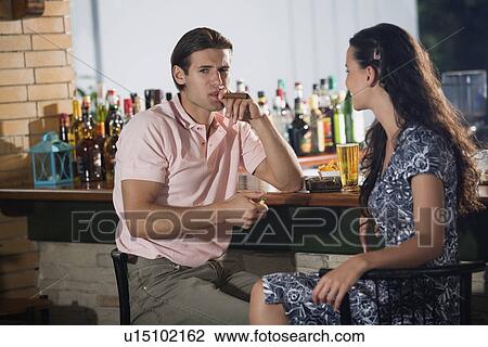 Stock Image - Couple in a bar, man lighting cigar. Fotosearch