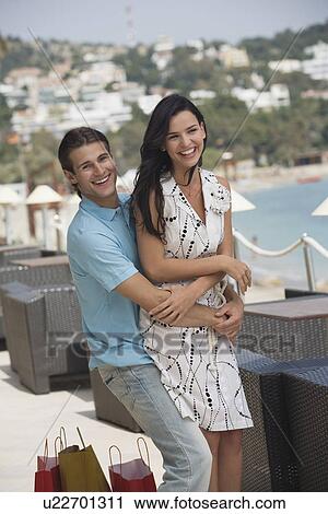 Stock Image - Couple with shopping bags embracing. Fotosearch
