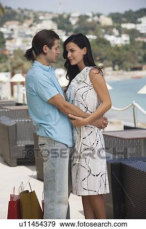 Stock Photo - Couple with shopping bags embracing. Fotosearch