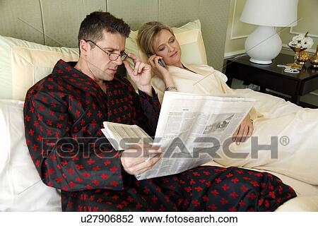 Stock Image - Mature couple relaxing in bed. Fotosearch