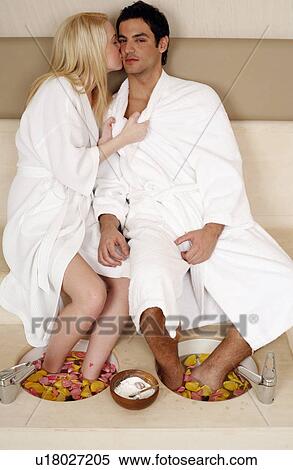 Stock Photography - A young couple enjoying a foot bath with rose petals. Fotosearch