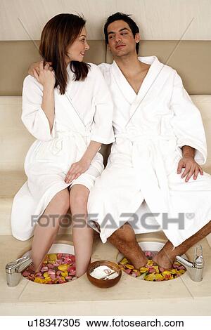 Stock Photography - A young couple enjoying a foot bath with rose petals. Fotosearch