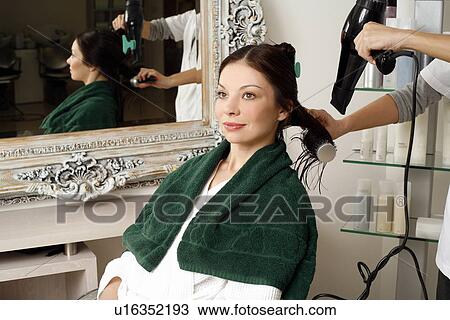Stock Image - Young woman having her hair curled. Fotosearch