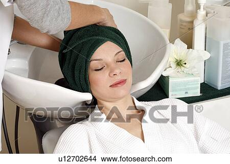 Picture - Young woman having her hair washed at a salon. Fotosearch
