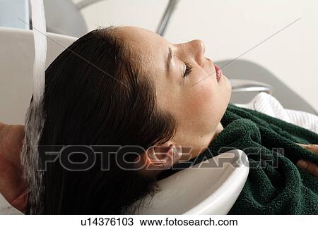 Stock Image - Young woman having her hair washed at a salon. Fotosearch