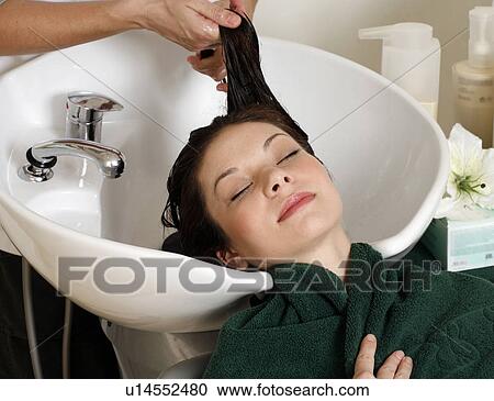 Stock Image - Young woman having her hair washed at a salon. Fotosearch