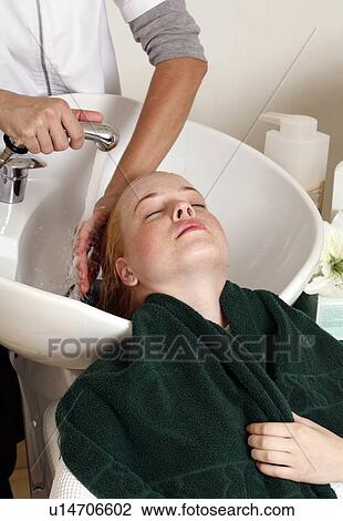 Stock Image - Young woman having her hair washed at a salon. Fotosearch