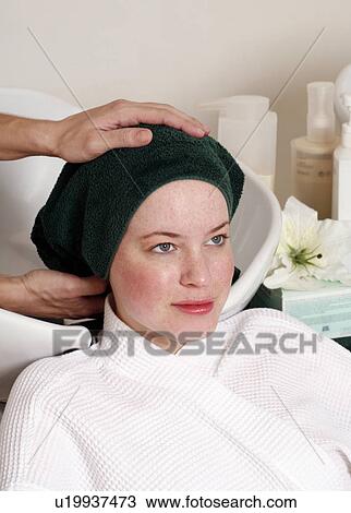 Stock Image - Young woman having her hair washed at a salon. Fotosearch