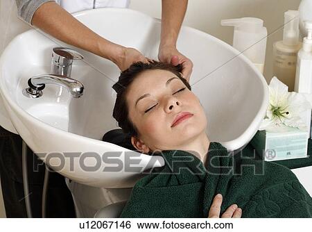Stock Photograph - Young woman having her hair washed at a salon. Fotosearch