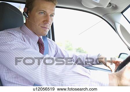 A Mid Adult Businessman Wearing a Headset and Driving a Car, Waist Up View Large Photo Image Stock Photo - A Mid Adult Businessman Wearing a Headset and Driving a Car, Waist Up. Fotosearch