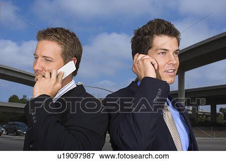 A Pair of Businessmen Talking on a Cellular Phone, Waist Up View Large Photo Image Stock Photo - A Pair of Businessmen Talking on a Cellular Phone, Waist Up. Fotosearch
