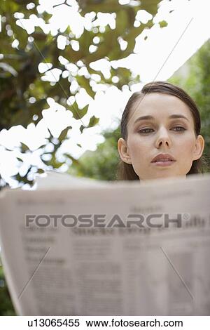 Stock Photography - A Young Adult Businesswoman Reading a Newspaper, Front View, Low Angle View, Differential Focus. Fotosearch