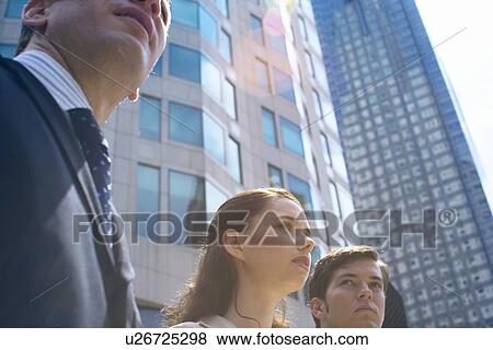 Stock Photo - Three Office Workers in Downtown, Low Angle View, Lens Flare. Fotosearch