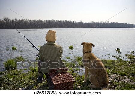Boy (12-14) fishing by river with pet dog, rear view View Large Photo Image Stock Photo - Boy (12-14) fishing by river with pet dog, rear view. Fotosearch