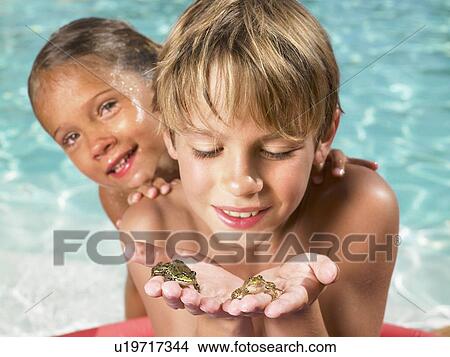 Picture - Brother and sister playing with frogs.. Fotosearch