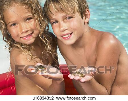 Stock Image - Brother and sister playing with frogs.. Fotosearch