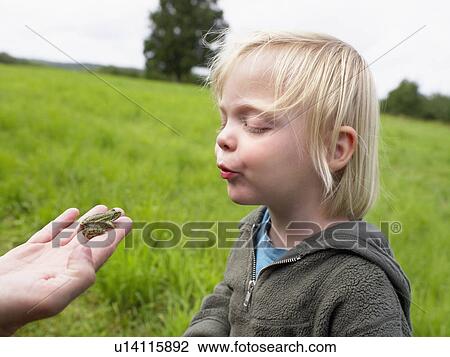 Young girl looking at a small frog held in a man's hand. View Large Photo Image Stock Image - Young girl looking at a small frog held in a man's hand.. Fotosearch