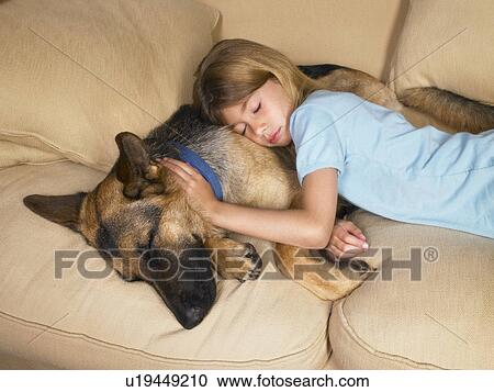 Stock Image - Young girl sleeping on her dog.. Fotosearch