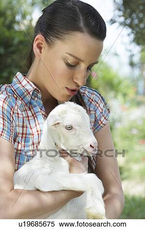 Stock Photography - Young girl with goat in arm calming it.. Fotosearch