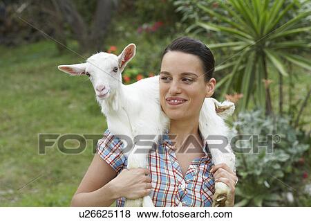 Stock Photo - Young girl with goat on shoulders looking at goat happy.. Fotosearch