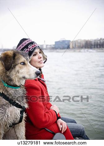 Young woman sitting by river with dog (focus on woman) View Large Photo Image Stock Image - Young woman sitting by river with dog (focus on woman). Fotosearch