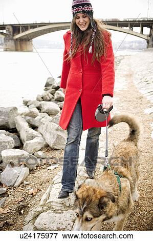 Young woman walking dog on lead by river, smiling View Large Photo Image Stock Photo - Young woman walking dog on lead by river, smiling. Fotosearch