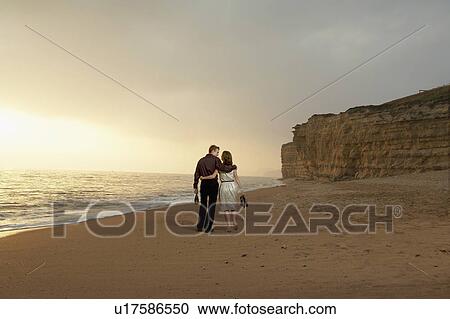 Stock Image - Couple walking together on beach.. Fotosearch