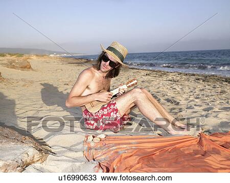 Stock Image - Man playing a ukulele at the beach.. Fotosearch
