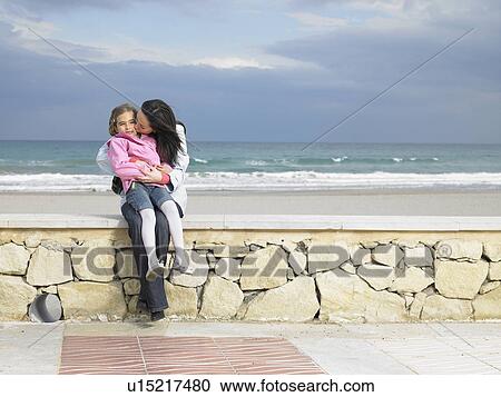 Mother and daughter (6-8) sitting on wall by beach View Large Photo Image Stock Image - Mother and daughter (6-8) sitting on wall by beach. Fotosearch