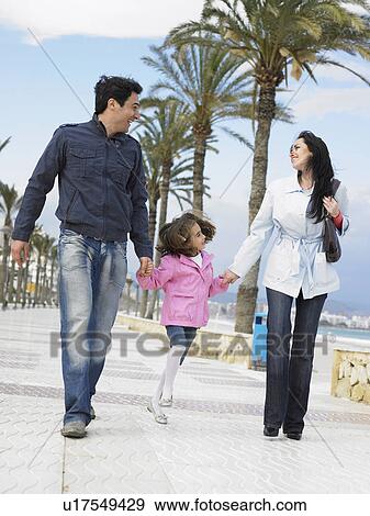 Mother and father walking along palm lined pavement by the sea with young daughter (6-8). Alicante, Spain. View Large Photo Image Stock Photo - Mother and father walking along palm lined pavement by the sea with young daughter (6-8). Alicante, Spain.. Fotosearch