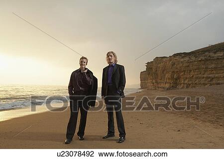 Two men standing on beach at sunset. View Large Photo Image Stock Image - Two men standing on beach at sunset.. Fotosearch