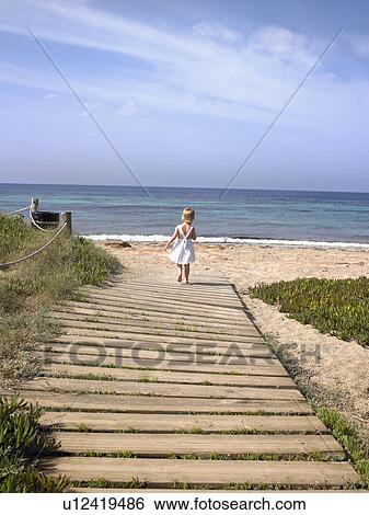 Young boy walking on a wooden path at the beach. View Large Photo Image Stock Photograph - Young boy walking on a wooden path at the beach.. Fotosearch