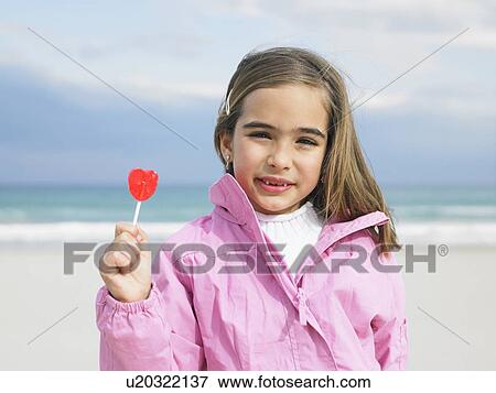 Young girl (6-8) holding lollipop in front of sea, close-up, portrait. Alicante, Spain. View Large Photo Image Stock Photo - Young girl (6-8) holding lollipop in front of sea, close-up, portrait. Alicante, Spain.. Fotosearch