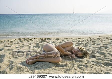 Stock Photo - Young girl lying on the beach sleeping.. Fotosearch