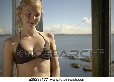 Stock Photo - Young woman by windows of beach house.. Fotosearch