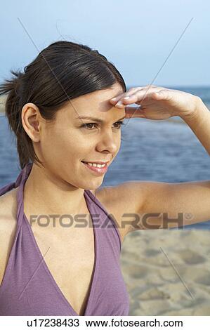 Young woman on beach portrait hand on forehead looking into distance smiling sea and sky in background. View Large Photo Image Stock Image - Young woman on beach portrait hand on forehead looking into distance smiling sea and sky in background.. Fotosearch
