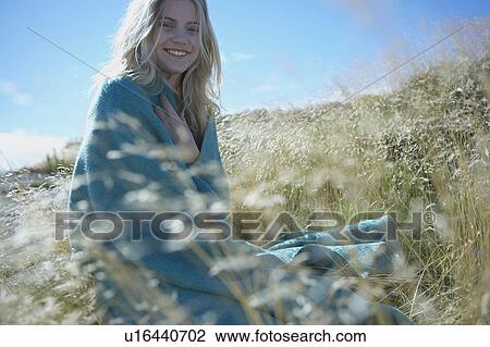 Stock Image - Young Woman Sitting in Long grass.. Fotosearch