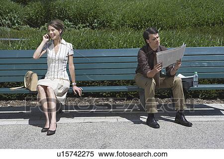 Stock Photography - Businessman and woman sitting on bench outside.. Fotosearch