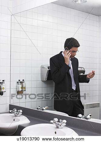 Man reflected in office washroom mirror using mobile phone View Large Photo Image Stock Image - Man reflected in office washroom mirror using mobile phone. Fotosearch