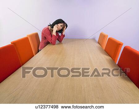 Stock Photo - Pensive businesswoman at meeting table giving a call.. Fotosearch