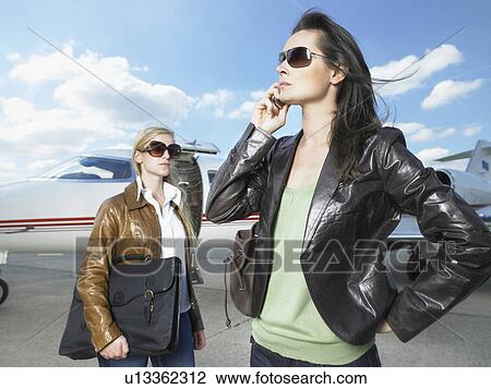 Two businesswomen standing in front of jet. View Large Photo Image Stock Image - Two businesswomen standing in front of jet.. Fotosearch