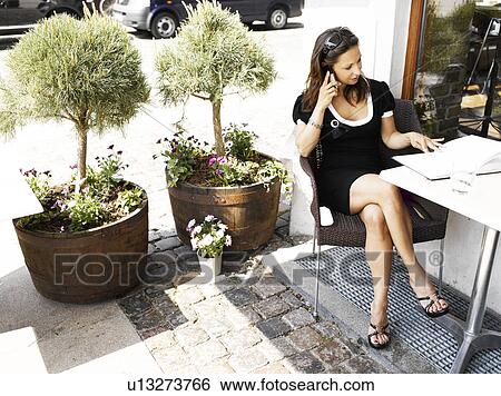 Stock Photograph - Woman on her cell phone at an outdoor restaurant. Fotosearch