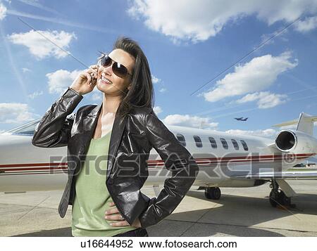 Woman standing next to private jet on phone. View Large Photo Image Stock Image - Woman standing next to private jet on phone.. Fotosearch