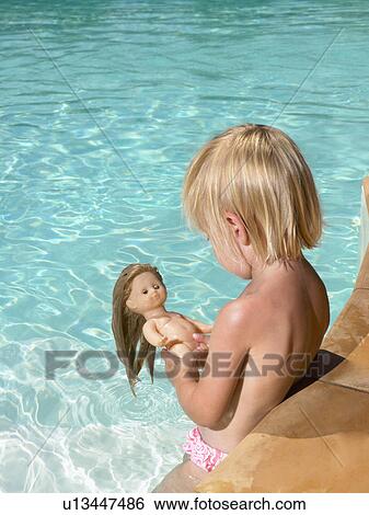 Stock Photograph - Young boy playing with a doll in a pool.. Fotosearch