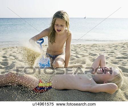 Young girl pouring sand onto a laughing young boy at the beach. View Large Photo Image Stock Photography - Young girl pouring sand onto a laughing young boy at the beach.. Fotosearch