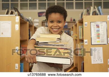 Stock Photo - Boy carrying books, smiling. Fotosearch