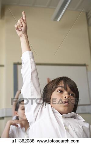 Stock Photo - Boy raising his hand in classroom. Fotosearch