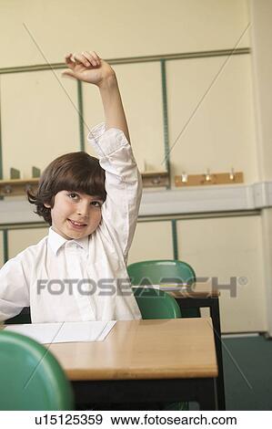 Stock Photo - Boy raising his hand in classroom. Fotosearch